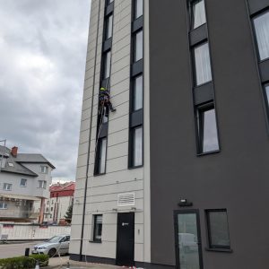alpinista myje okna w hotelu na linie
